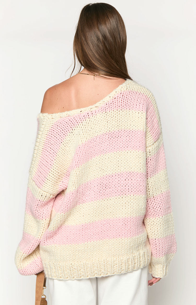 Rear view of a pink and cream striped chunky knit sweater with a wide off-the-shoulder neckline and ribbed hem