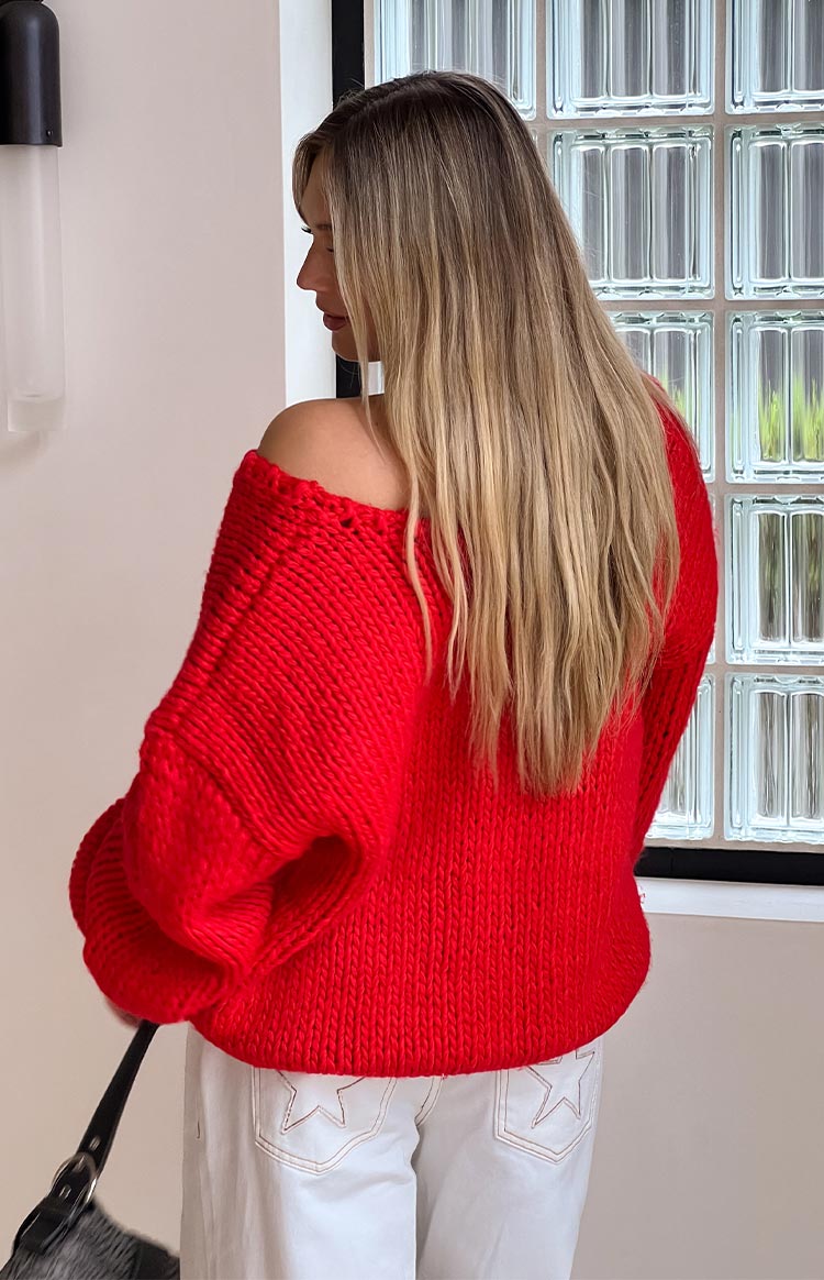 Rear view of a red chunky knit sweater with an off-shoulder neckline and loose sleeves