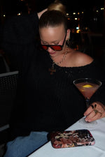 Black chunky knit sweater worn off-shoulder with a relaxed fit