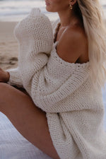 Close-up of a cream chunky knit sweater draped off the shoulder, showing the thick ribbed texture