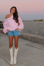 Light pink chunky knit sweater with an oversized fit, wide off-shoulder neckline, and voluminous balloon sleeves