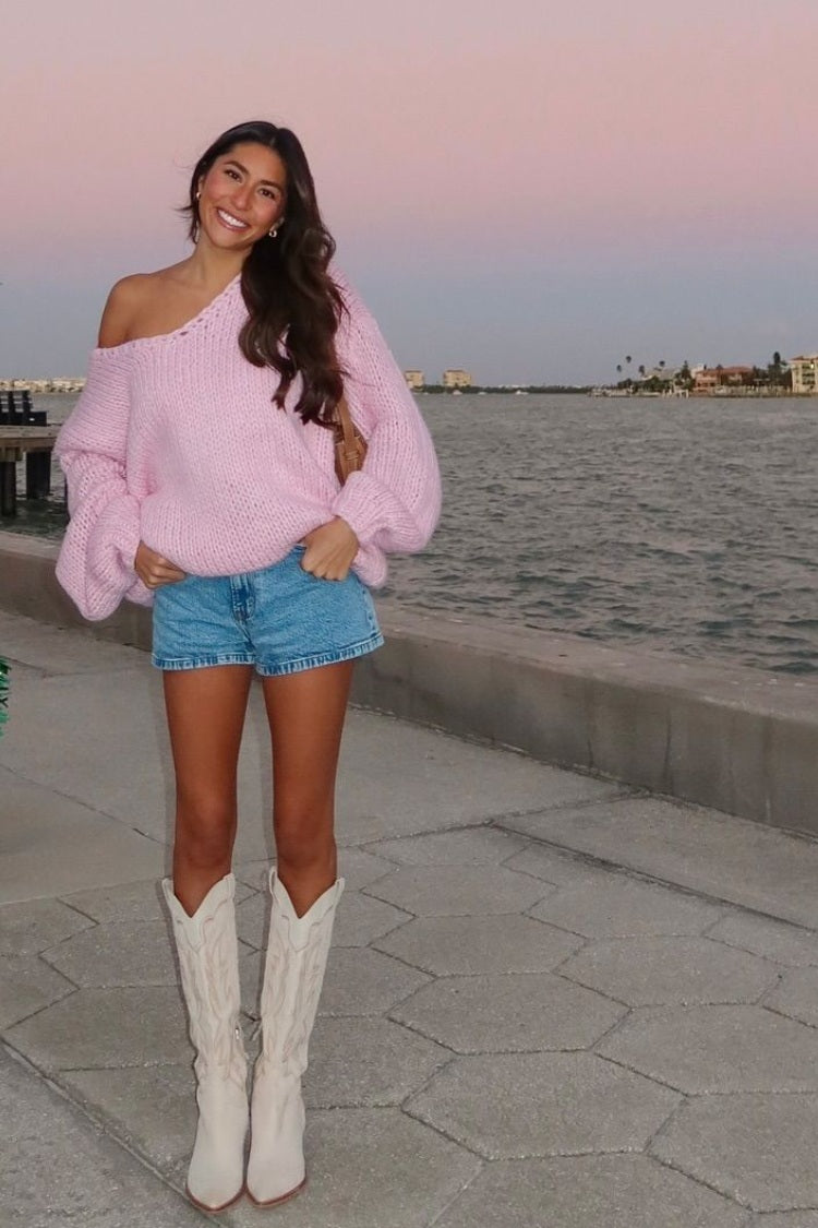 Light pink chunky knit sweater with an oversized fit, wide off-shoulder neckline, and voluminous balloon sleeves