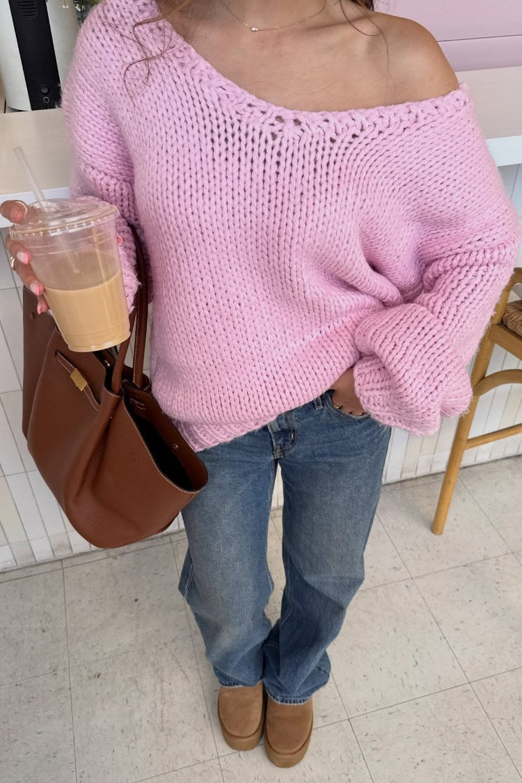 Light pink chunky knit sweater with a wide off-shoulder neckline and long slouchy sleeves