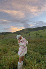 Oversized pink and white striped chunky knit sweater with wide long sleeves and an off-shoulder neckline