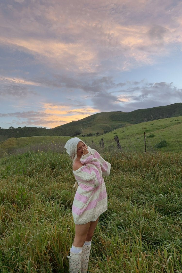 Oversized pink and white striped chunky knit sweater with wide long sleeves and an off-shoulder neckline