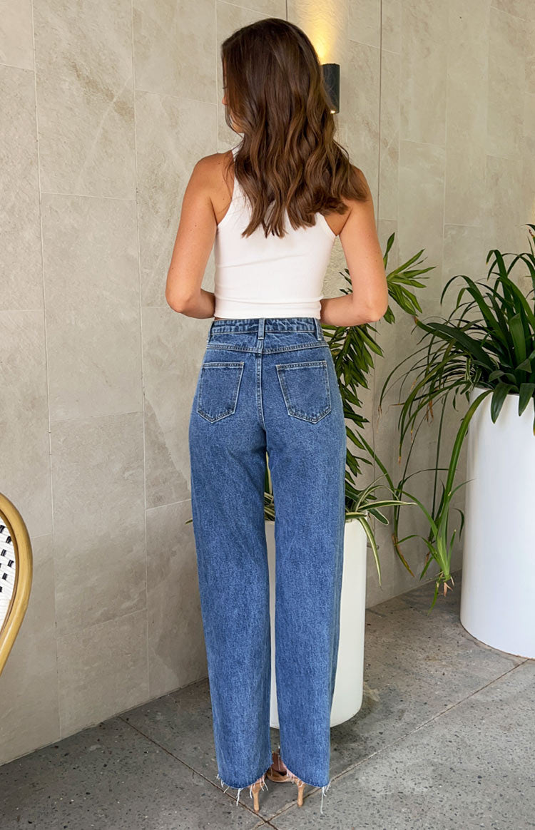 Rear view of mid wash blue high waisted jeans with back pockets, belt loops, and a raw hem