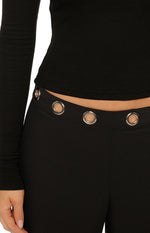 Close-up of the black straight leg pants waistband with silver eyelet details