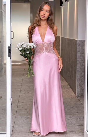 A long- light pink satin gown featuring a deep V-neck halter neckline and a sheer lace bodice with an empire waist. This elegant dress is suitable for a formal event or a romantic evening.