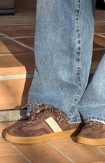 Side view of brown suede and fabric sneakers with leopard print laces and a white side stripe