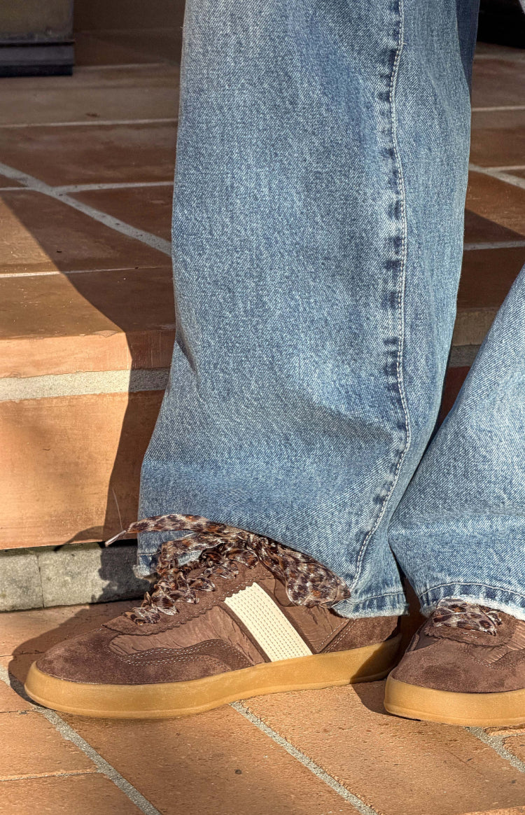 Side view of brown suede and fabric sneakers with leopard print laces and a white side stripe