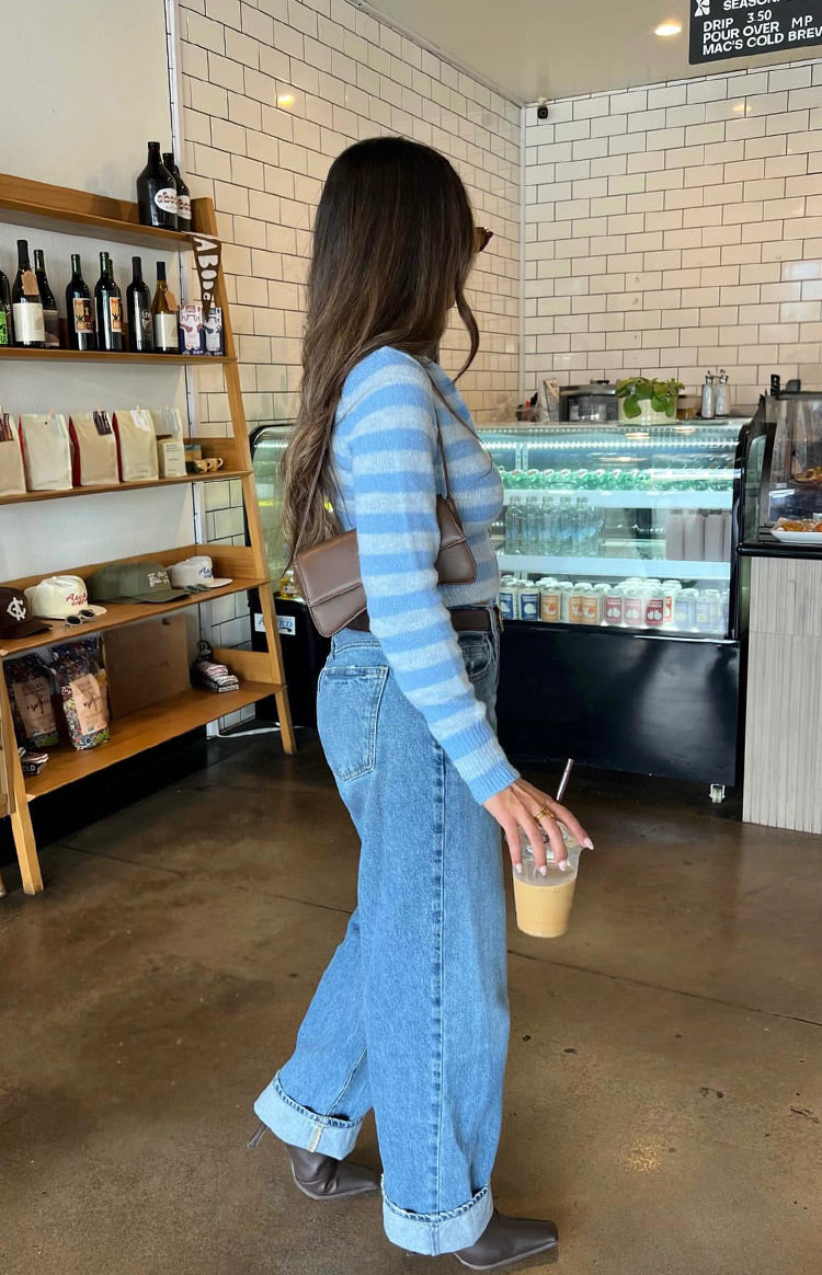 Side view of a blue and white striped knit sweater with long sleeves and a cropped, fitted silhouette