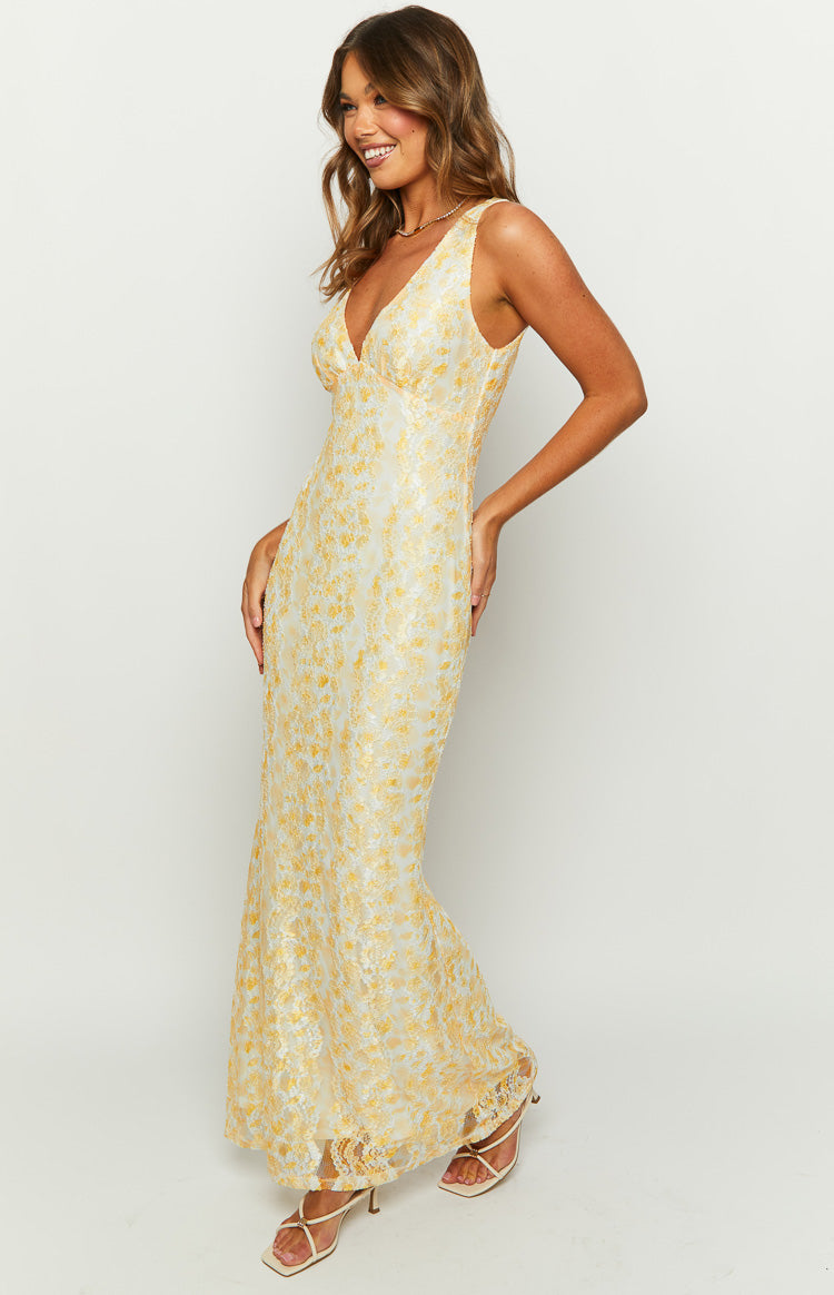 Angled view of a yellow floral lace maxi dress with a V-neckline and fitted silhouette