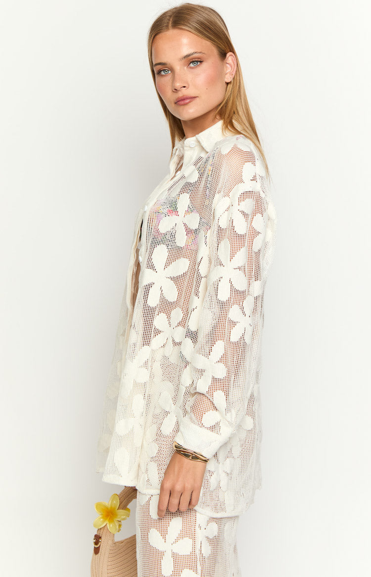 Side view of the white sheer long sleeve mini dress, showing the open-knit floral pattern and collared neckline