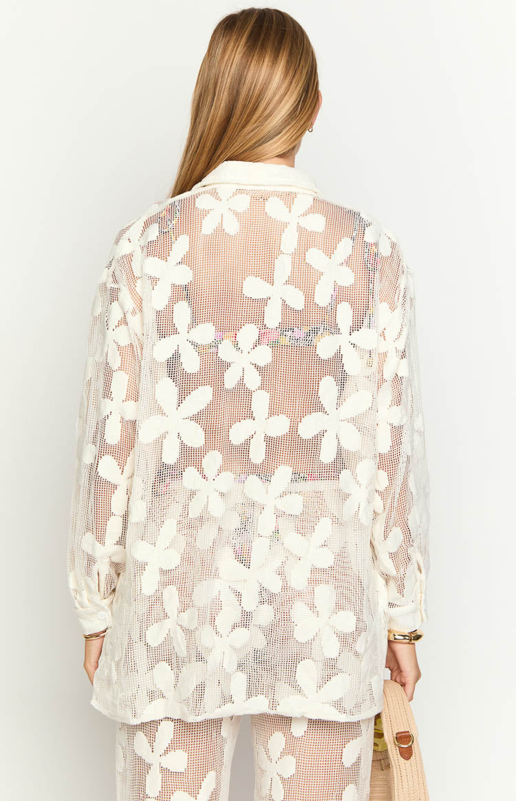 Rear view of a white sheer open-knit long sleeve mini dress with a floral pattern