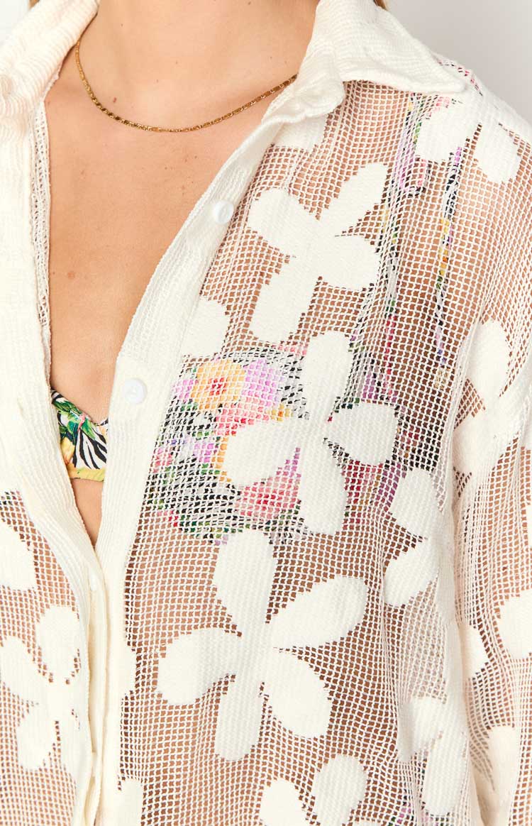 Close-up of the white sheer open-knit mini dress with floral crochet pattern and button-front