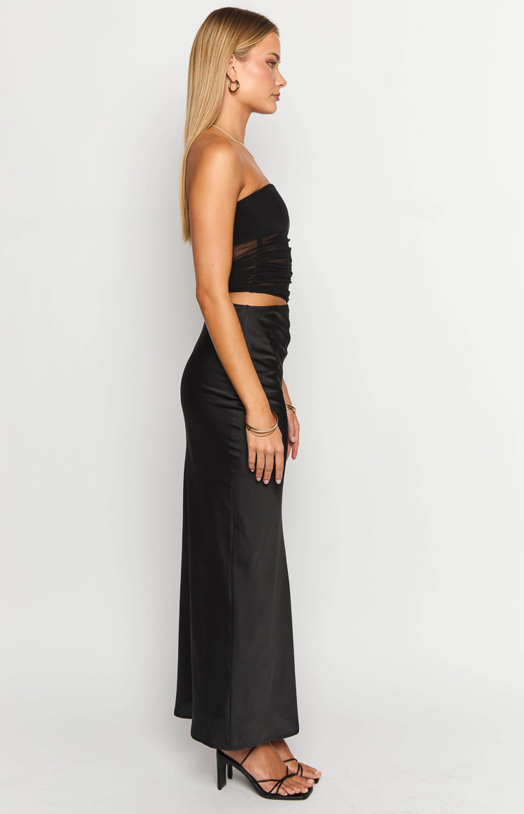 Side view of a black strapless satin maxi dress with a ruched mesh bodice and flowing skirt