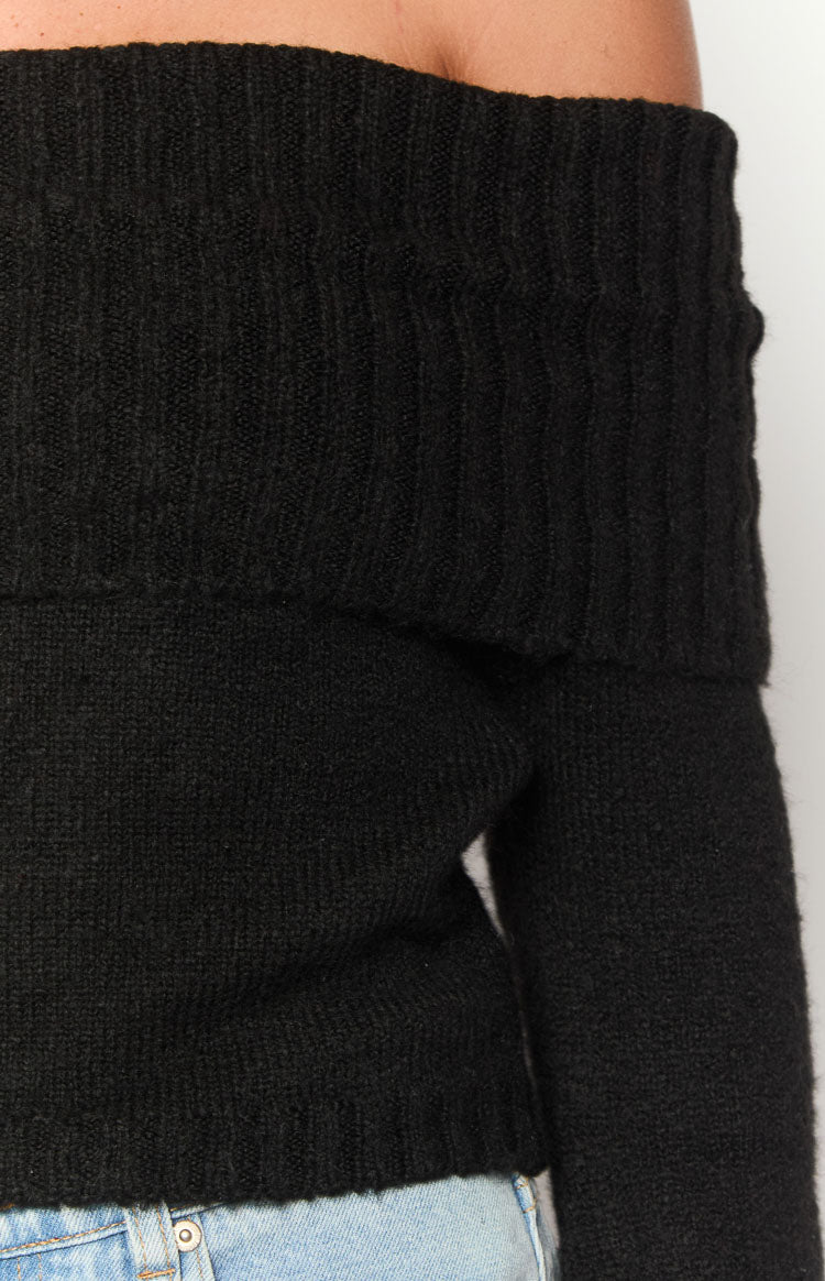 Close-up of the black off-shoulder sweater showing the ribbed fold-over neckline and soft knit texture