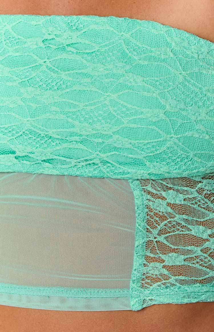 Close-up showing the intricate teal lace pattern and sheer mesh panel of the corset top