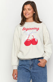 Oat marle crew neck sweater featuring a red 'Beginning' text and a cherry graphic with white ribbon detail