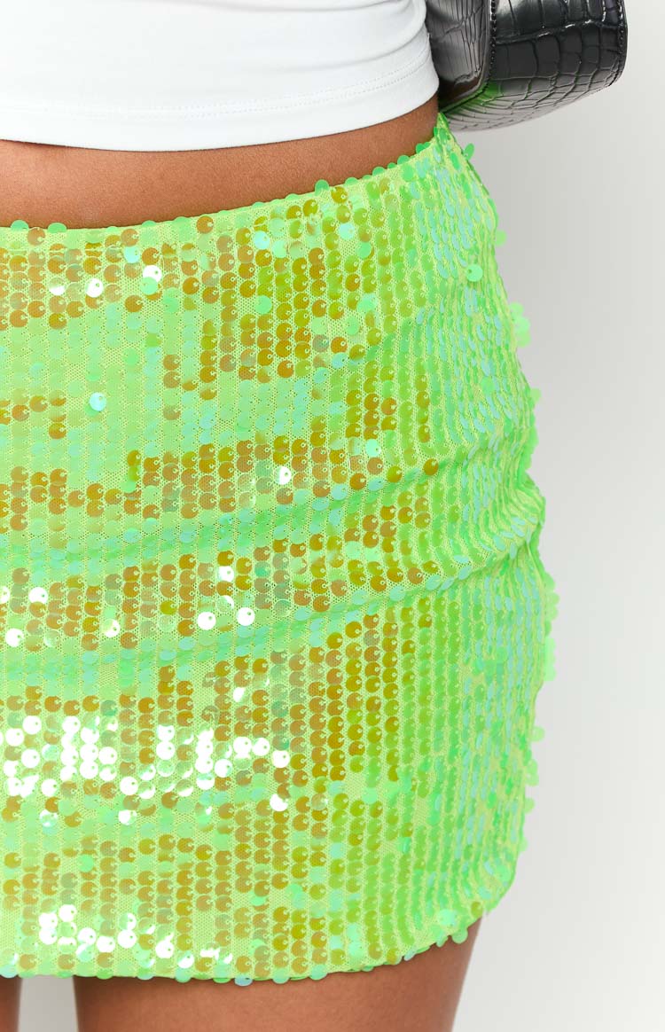 Close-up of the side of a lime green sequin mini skirt showing iridescent sequins and subtle side ruching