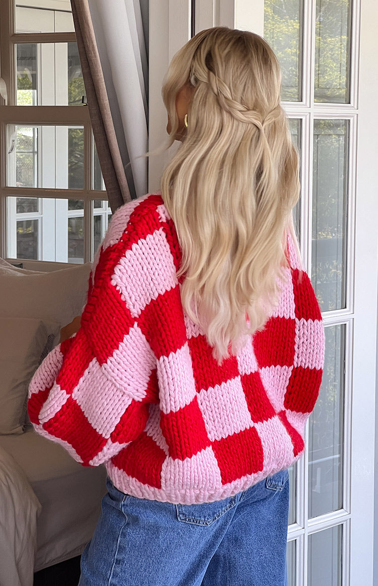 Rear view of an oversized pink and red checkered chunky knit cardigan with voluminous long sleeves