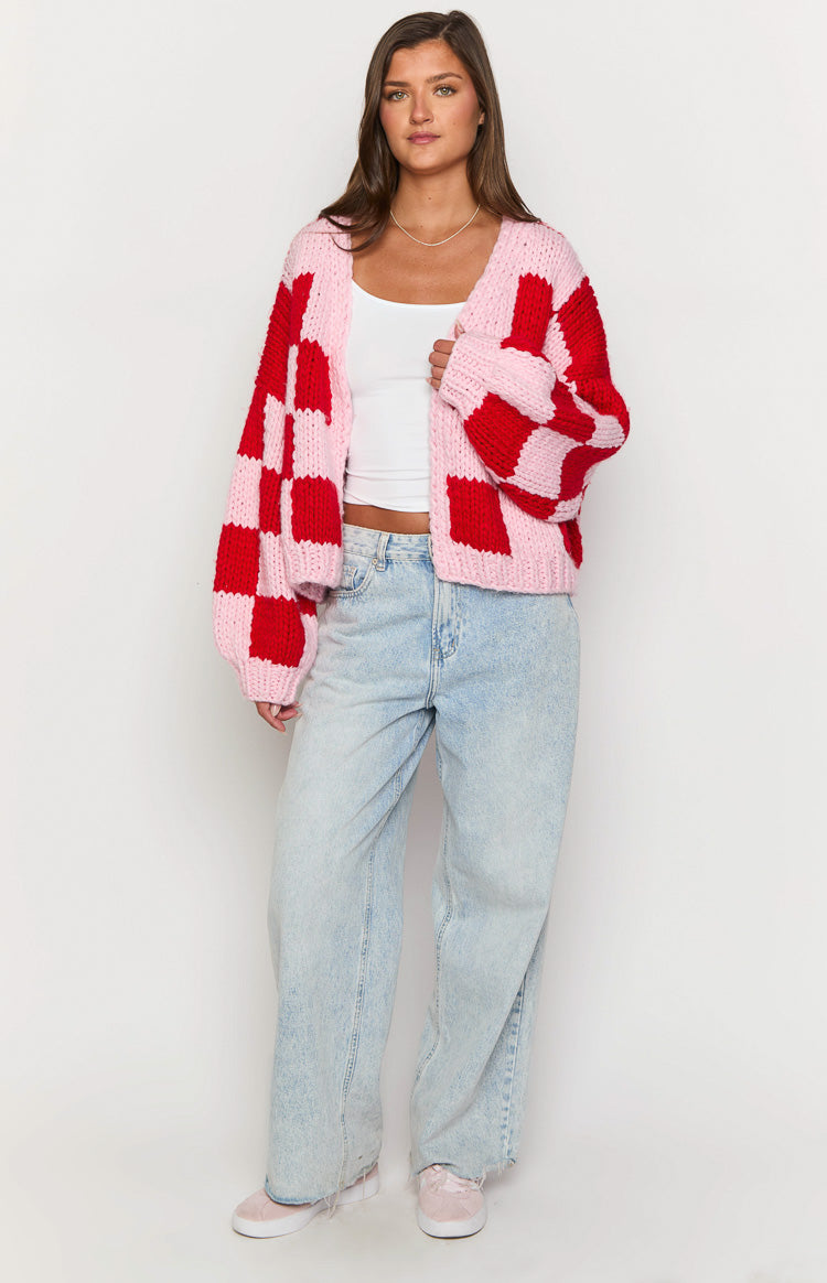 Front view of a pink and red checkered chunky knit cardigan worn open showing its relaxed fit and balloon sleeves