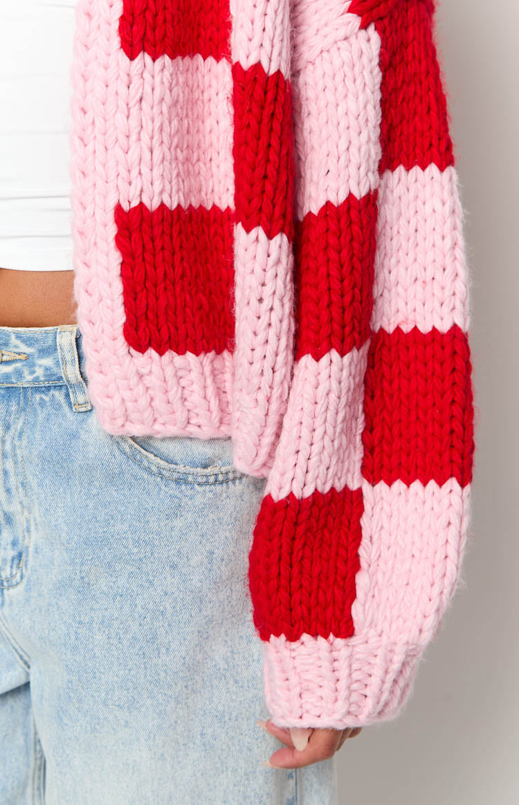 Close-up of the chunky pink and red checkered knit cardigan showing the ribbed cuff and hem