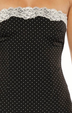 Close-up of the white floral lace trim on the strapless neckline of a black polka dot mini dress