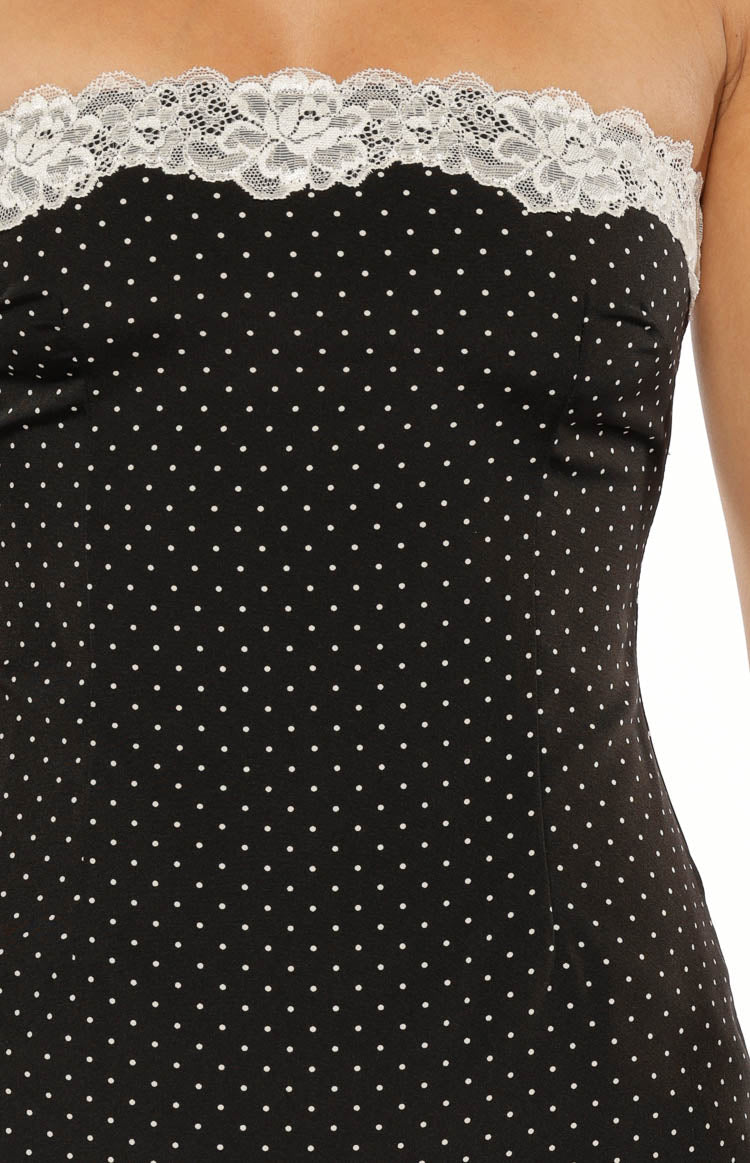 Close-up of the white floral lace trim on the strapless neckline of a black polka dot mini dress