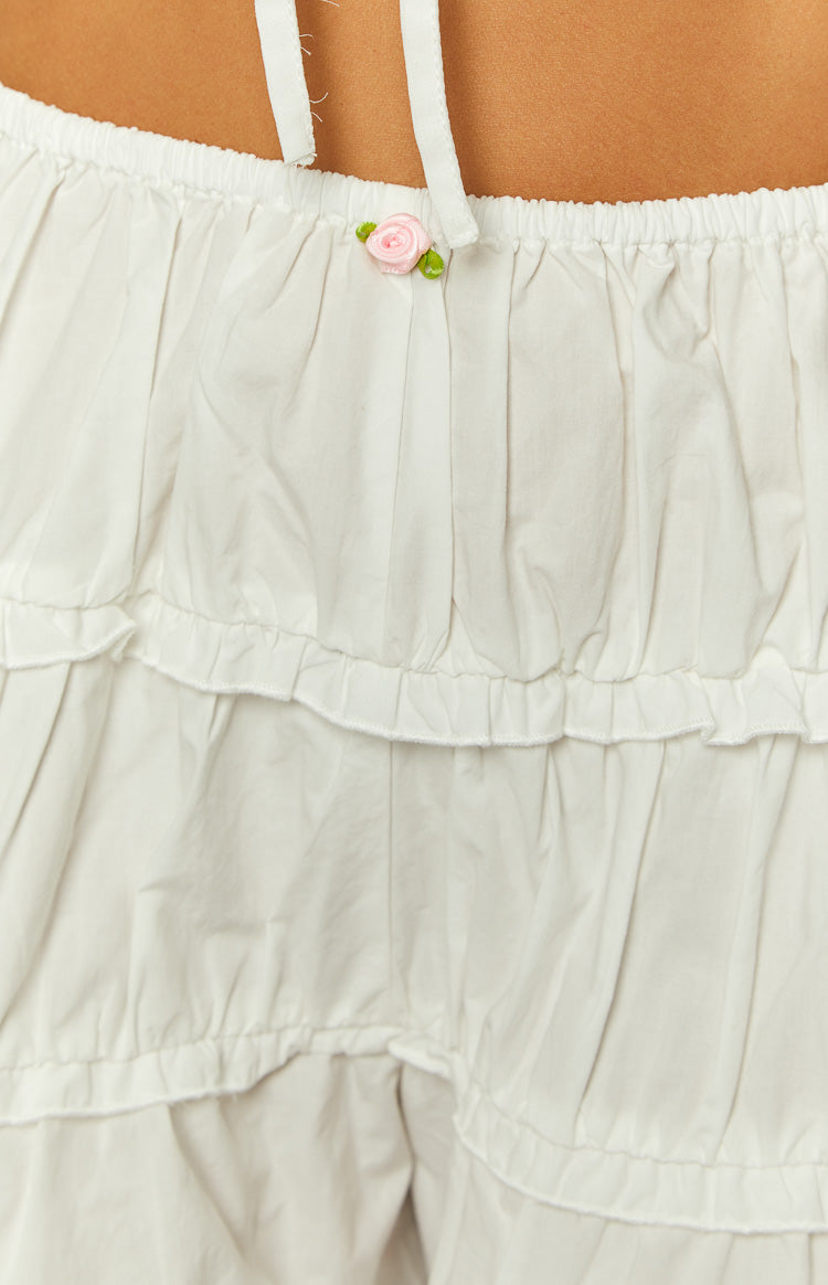 Close-up of the elasticated waist of white shorts with a small pink rose detail and two ruffled tiers