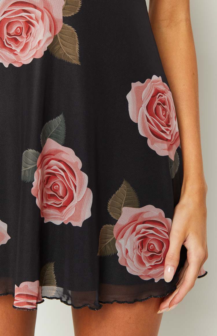 Close-up of the black mini dress fabric with pink rose floral print and lettuce edge hem