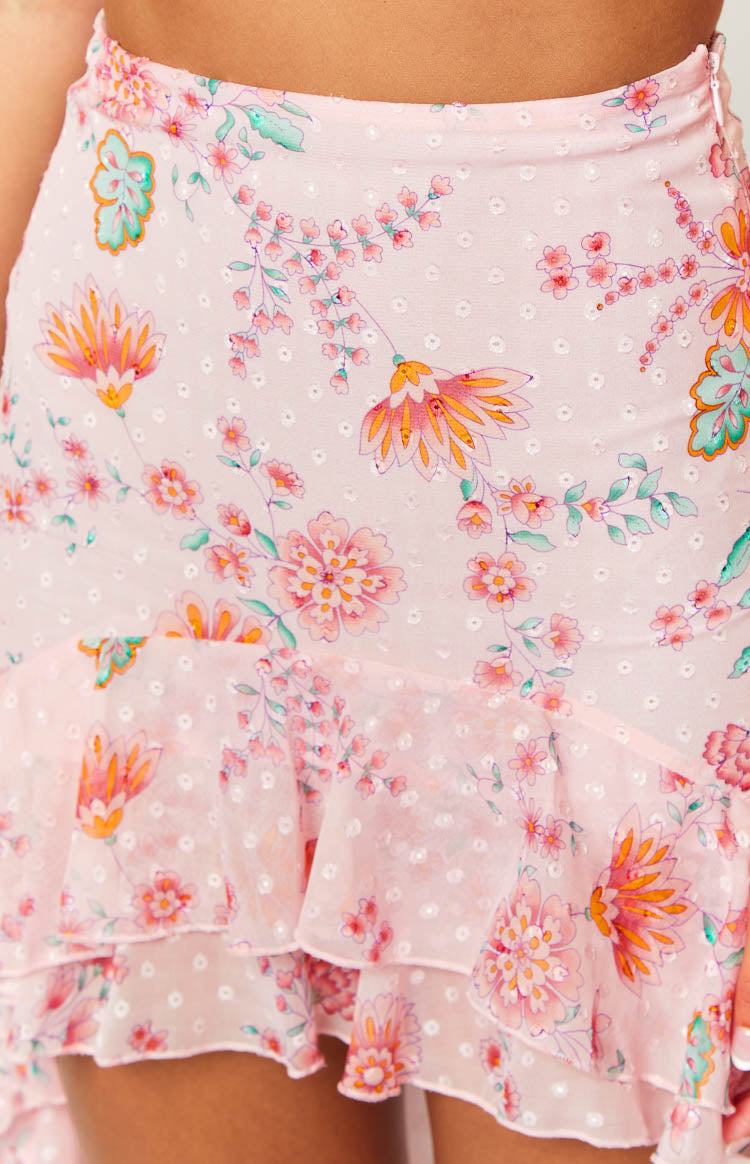 Close-up of the pink floral maxi skirt showing the white swiss dot texture and tiered ruffle hem