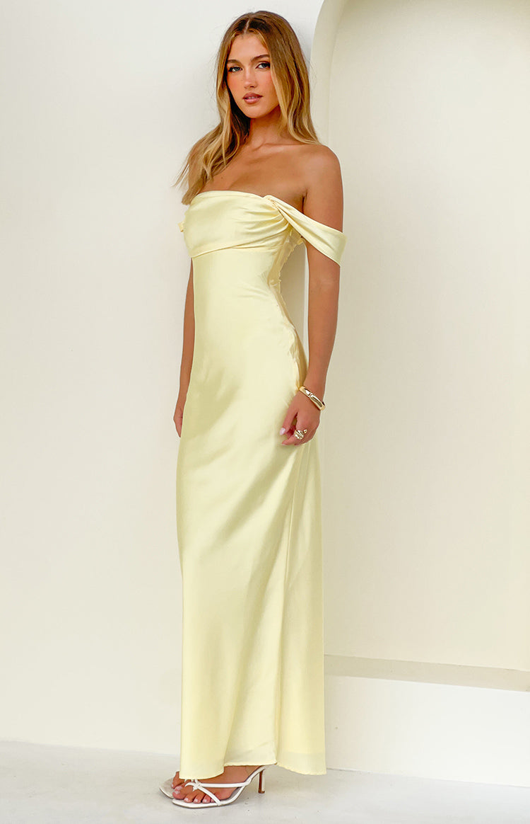 Light yellow off-shoulder maxi dress featuring a draped neckline and a long flowing skirt