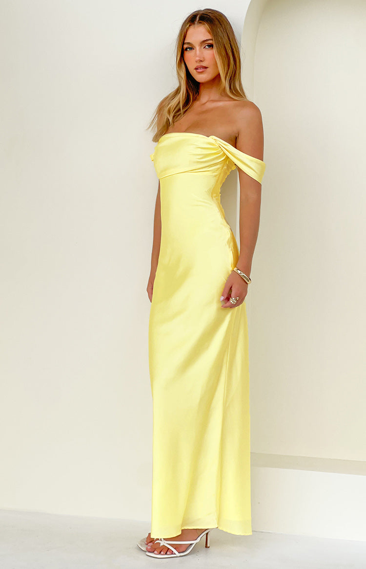 Light yellow off-shoulder maxi dress featuring a draped neckline and a long flowing skirt