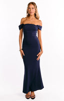 A full-length image of a model wearing a form-fitting navy blue off-the-shoulder maxi dress with a straight neckline.