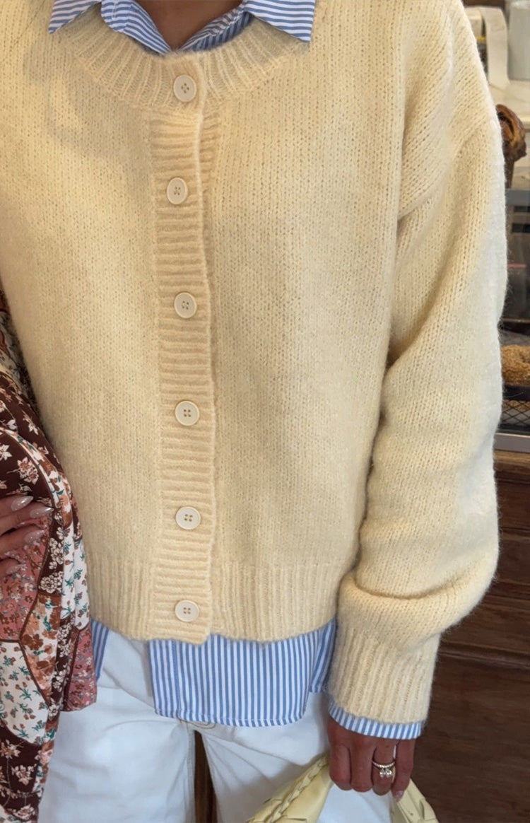 Close-up of the fuzzy knit texture, ribbed placket, and cream buttons on the butter yellow cardigan