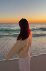 Side and back view of a butter yellow knit cardigan with a relaxed fit, long sleeves, and ribbed cuffs and hem