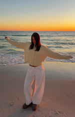 Full length view of white denim barrel leg jeans with a wide, curved silhouette and contrast stitching