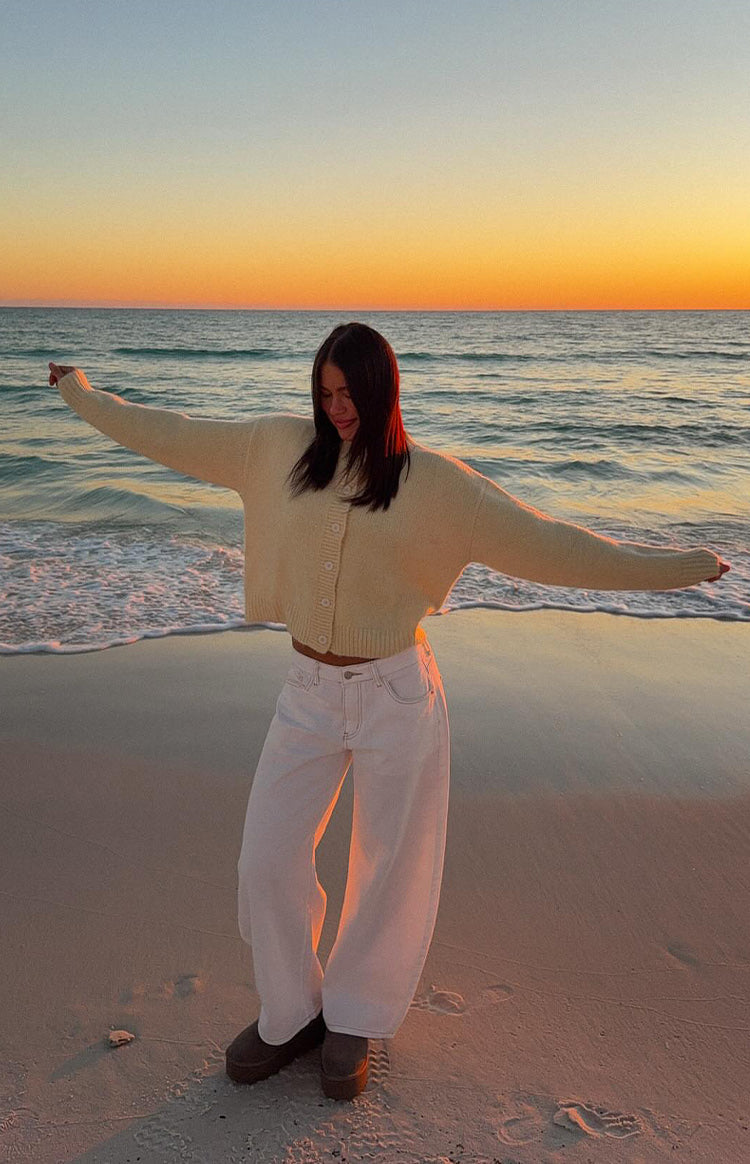Full length view of white denim barrel leg jeans with a wide, curved silhouette and contrast stitching