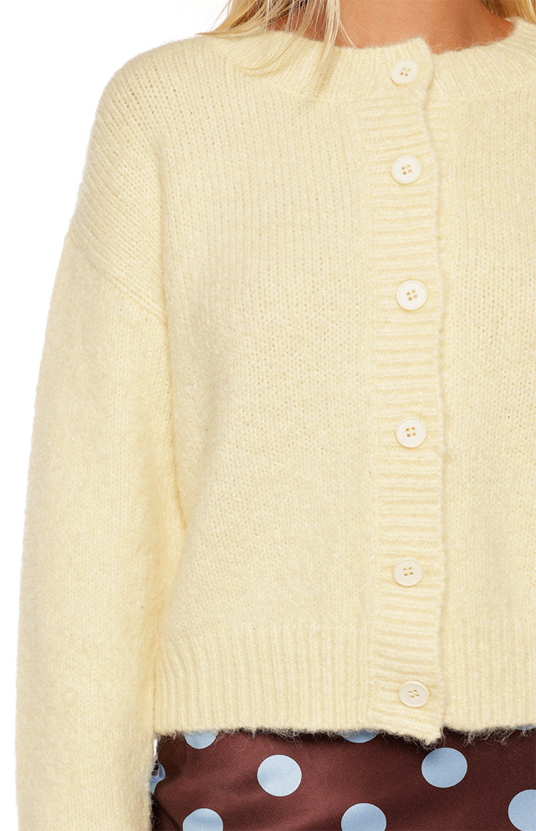 Detail shot of the soft butter yellow knit cardigan with a front button placket, cream buttons, and ribbed hem