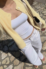 Close-up of a butter yellow knit cardigan worn open, showing the ribbed cuffs and matching buttons