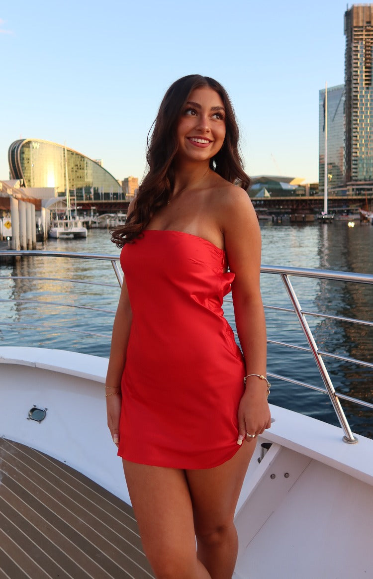 Side view of a red strapless mini dress with a fitted silhouette and subtle side ruching