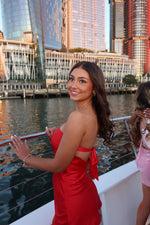 Side view of a red strapless mini dress with a tie-back detail forming a bow at the waist