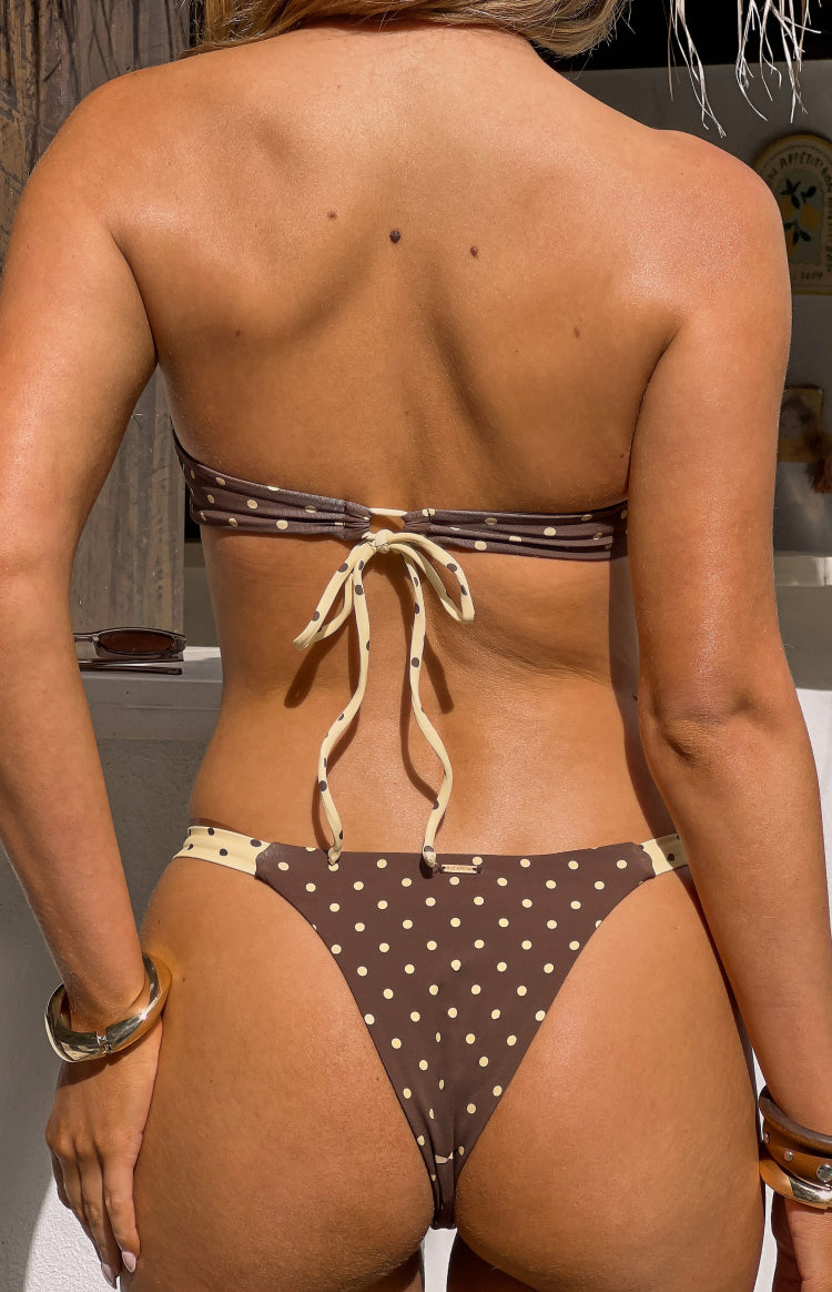 Rear view of brown polka dot bikini bottoms with a cheeky cut and cream side trim