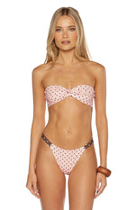 Pink polka dot bikini bottoms with a V-cut front and thin brown hip straps
