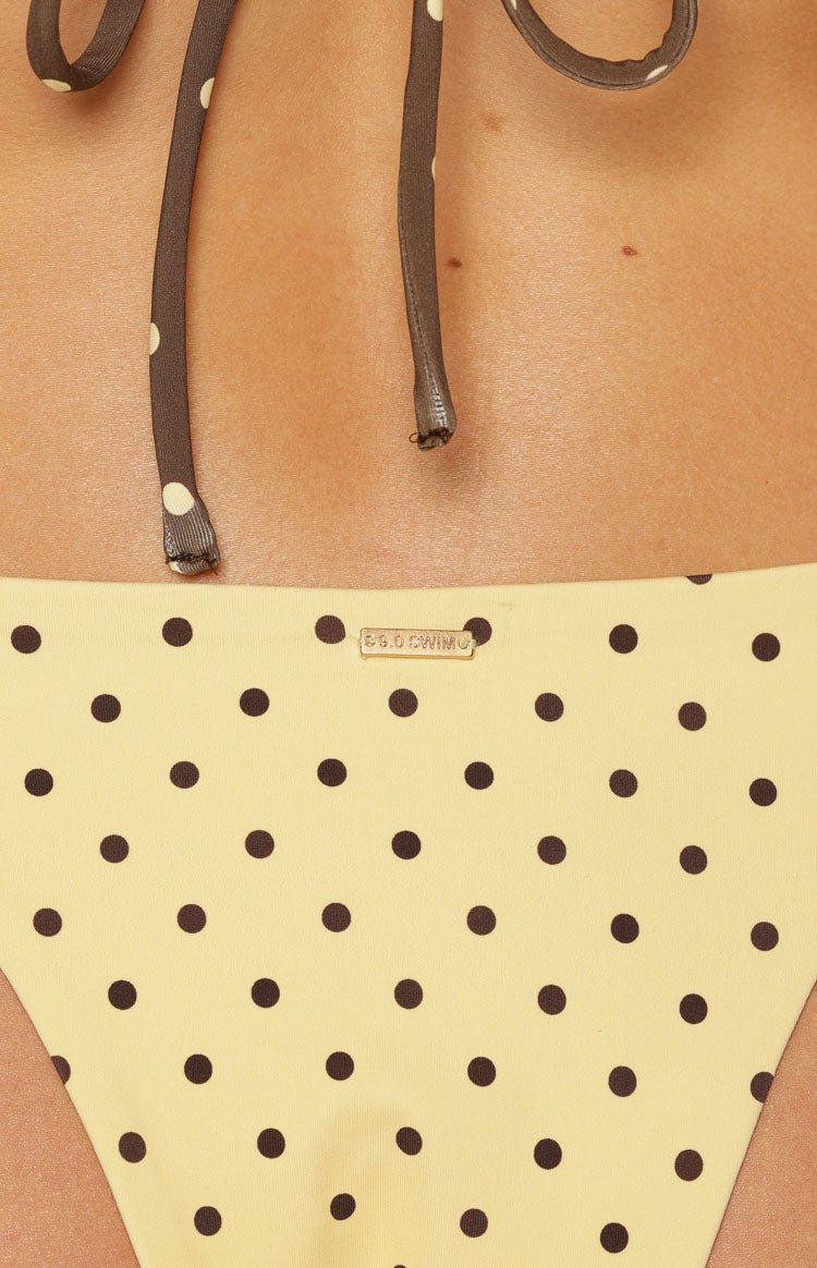 Close-up of the yellow polka dot bikini bottoms with a small gold BB.G.SWIM tag at the waistline