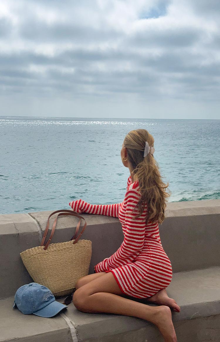 Side view of a red and white striped knit mini dress with long sleeves and a fitted silhouette