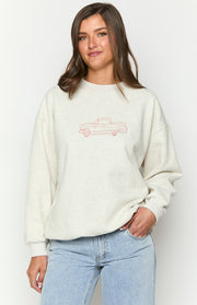 Close-up of the red embroidered classic car graphic on the front of a grey crew neck sweater