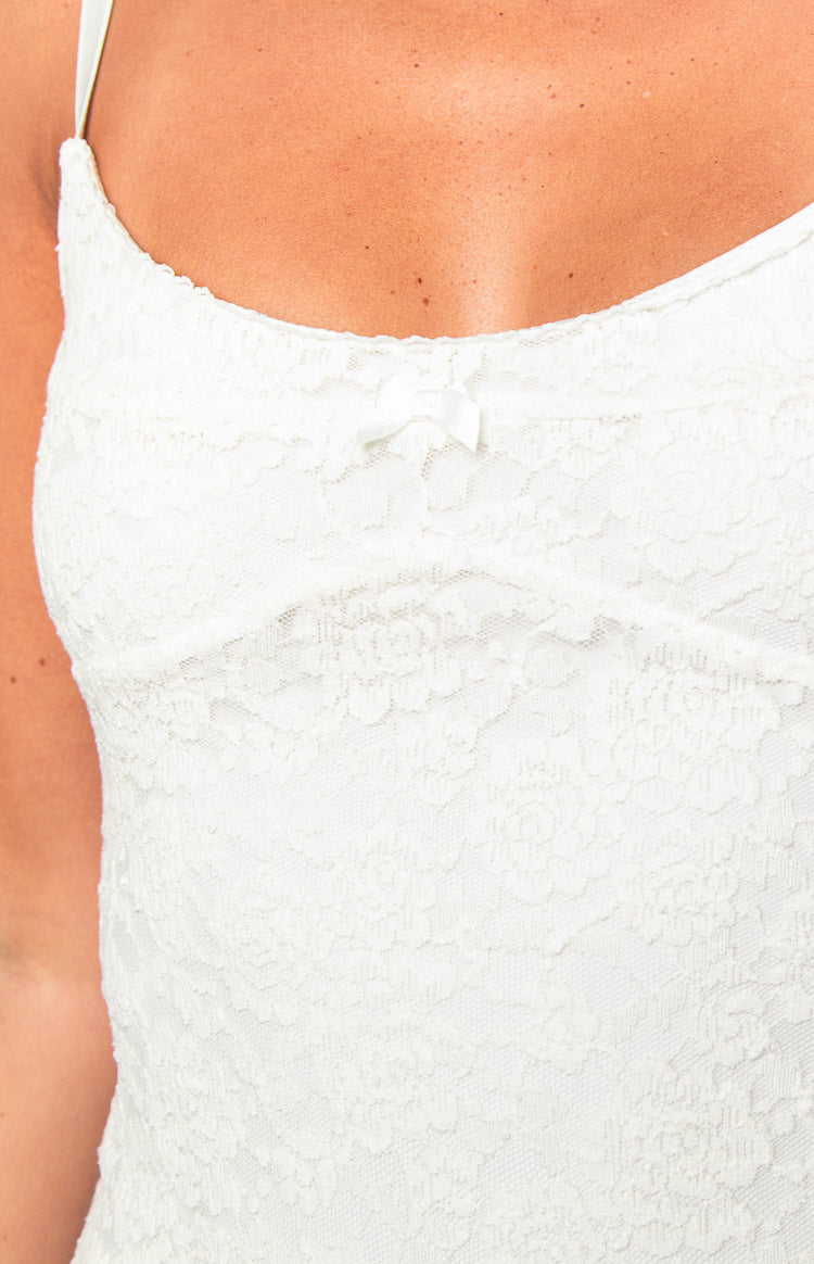 Close-up of the white floral lace pattern and small satin bow detail on the dress bodice