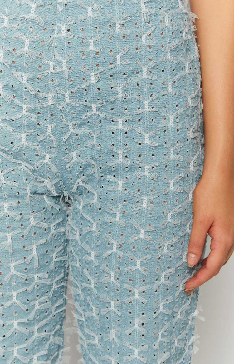 Close-up of the blue chambray fabric with white bow embroidery and cutouts